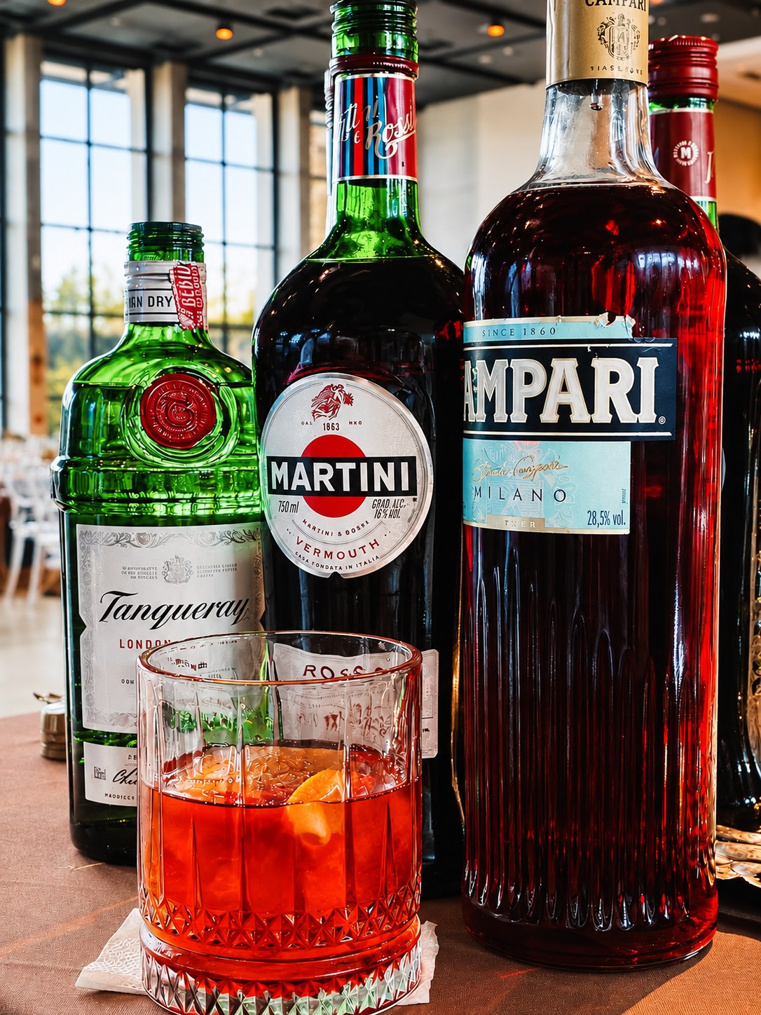 Drink vermelho com gelo junto a garrafas