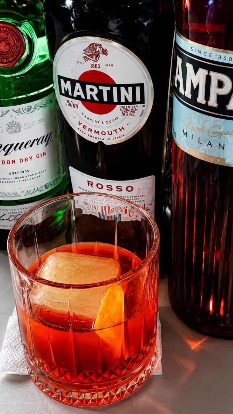 Coquetel vermelho junto a garrafas no bar