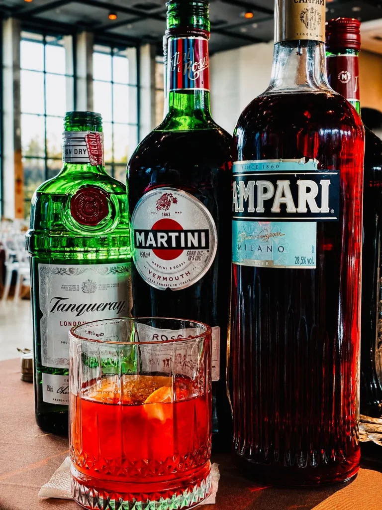 Drink vermelho com gelo junto a garrafas