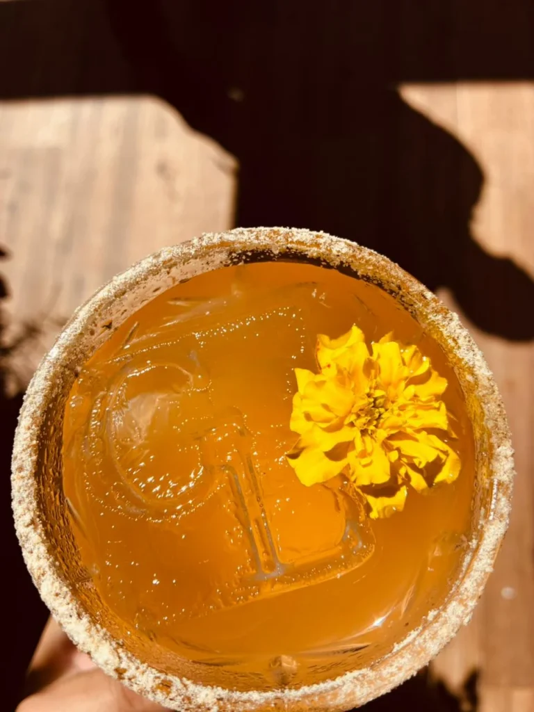 Coquetel dourado com gelo e flor amarela