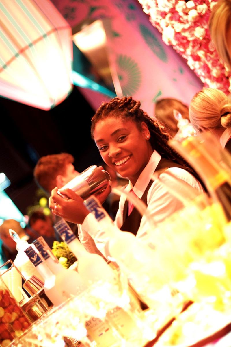 Integrante da equipe preparando drink e sorrindo